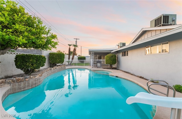 1009 Ironwood Dr, Las Vegas, NV 89108 - pool at dusk with a water slide, a fenced backyard, and a pool with connected hot tub