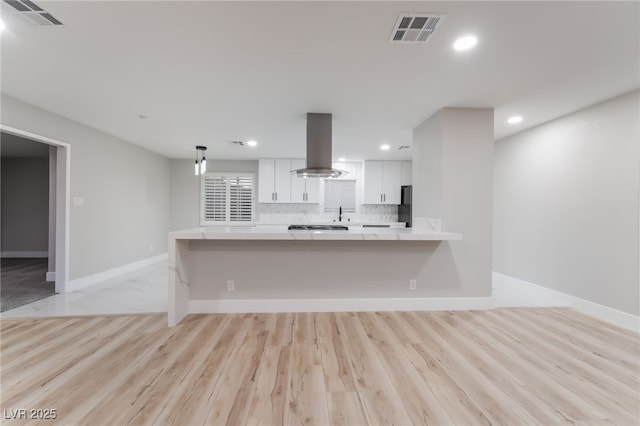 1009 Ironwood Dr, Las Vegas, NV 89108 - kitchen featuring island exhaust hood, light countertops, white cabinets, recessed lighting, and freestanding refrigerator