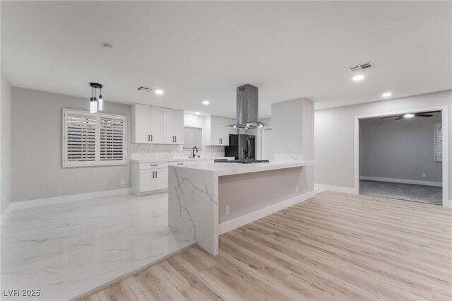 1009 Ironwood Dr, Las Vegas, NV 89108 - kitchen featuring island range hood, freestanding refrigerator, white cabinetry, a peninsula, and light wood-style floors