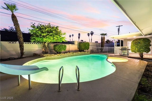 1009 Ironwood Dr, Las Vegas, NV 89108 - pool at dusk with a fenced backyard and a water slide