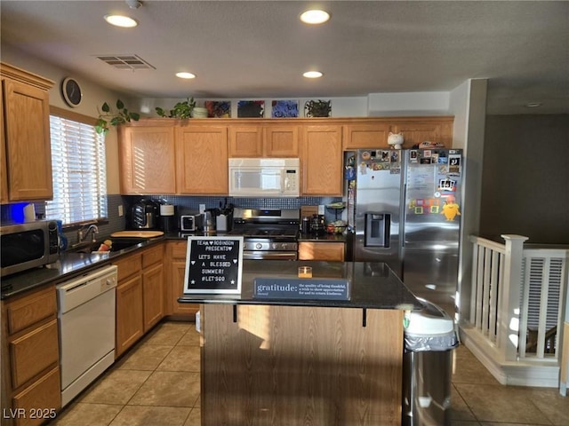 8949 Brian Christopher Ave, Las Vegas, NV 89149 - kitchen with appliances with stainless steel finishes, light tile patterned floors, a kitchen island, backsplash, and a breakfast bar area