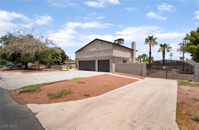 5676 Birchwood Cir, Las Vegas, NV 89120 - view of front facade with a gate, driveway, an attached garage, stucco siding, and a chimney