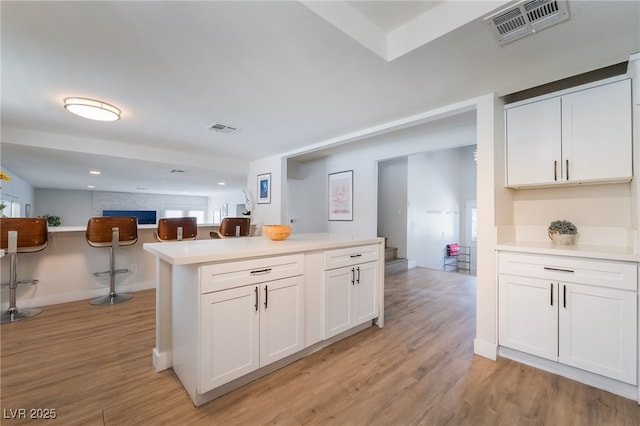 5676 Birchwood Cir, Las Vegas, NV 89120 - kitchen with light wood-type flooring, white cabinetry, light countertops, a center island, and open floor plan