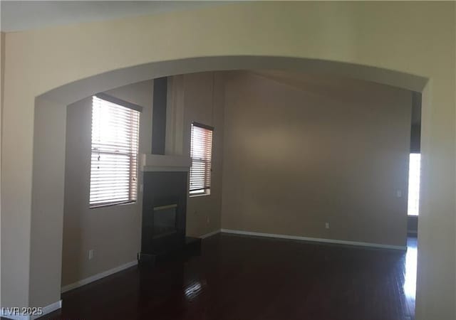 7414 Page Ranch Ct, Las Vegas, NV 89131 - unfurnished living room featuring plenty of natural light, dark wood finished floors, arched walkways, and a glass covered fireplace