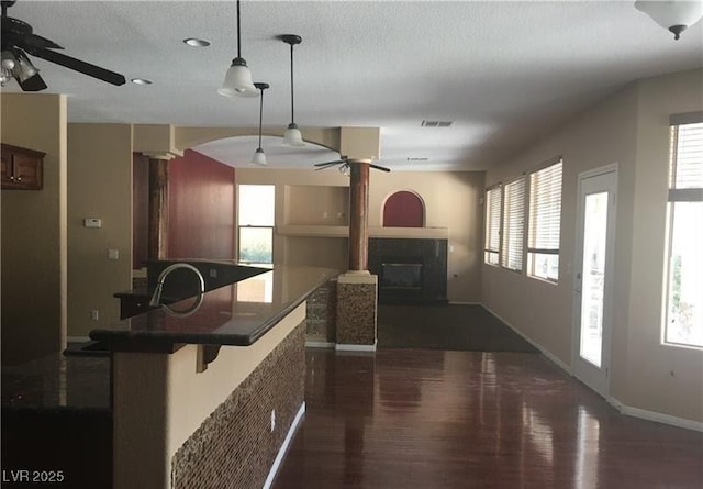 7414 Page Ranch Ct, Las Vegas, NV 89131 - kitchen with a ceiling fan, dark wood finished floors, dark countertops, a glass covered fireplace, and pendant lighting