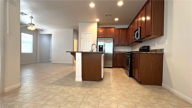 7469 Paces Mill Ct, Las Vegas, NV 89113 - kitchen with stainless steel appliances, ceiling fan, a kitchen bar, light tile patterned floors, and a center island with sink
