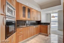 2877 Paradise Rd Unit 904, Las Vegas, NV 89109 - kitchen with stainless steel microwave, glass insert cabinets, and brown cabinets