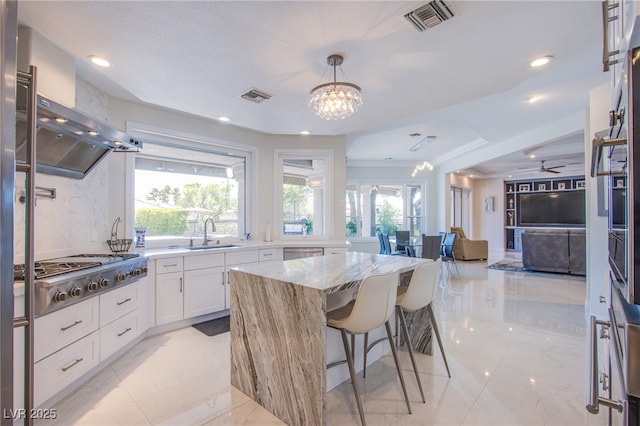 1890 Pago Ct, Las Vegas, NV 89117 - kitchen with stainless steel gas cooktop, light stone countertops, plenty of natural light, white cabinets, and recessed lighting