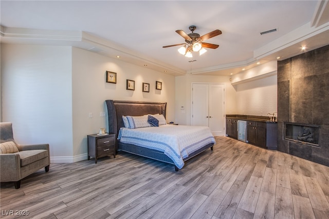 1890 Pago Ct, Las Vegas, NV 89117 - bedroom with light wood-style floors, beverage cooler, recessed lighting, a tile fireplace, and ceiling fan