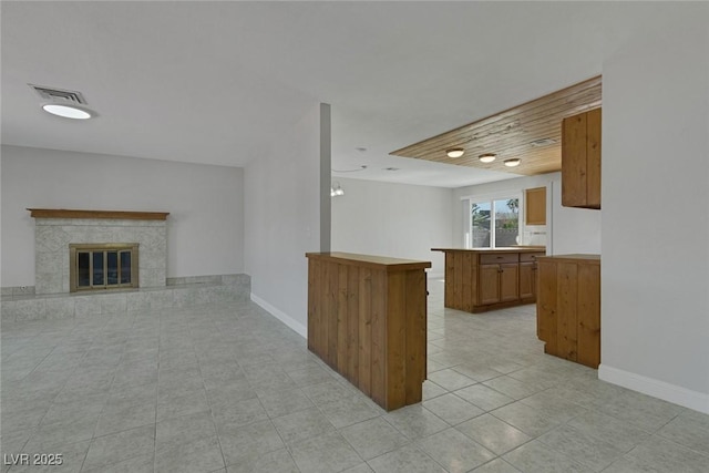 1841 Feather Way, Las Vegas, NV 89108 - kitchen with open floor plan, brown cabinets, light tile patterned floors, a peninsula, and a tile fireplace