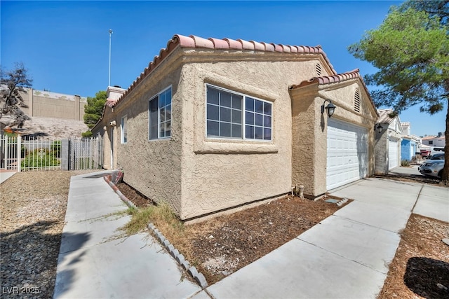 2165 Saint Paul Way, Las Vegas, NV 89104 - view of side of property with stucco siding, an attached garage, driveway, and a tile roof