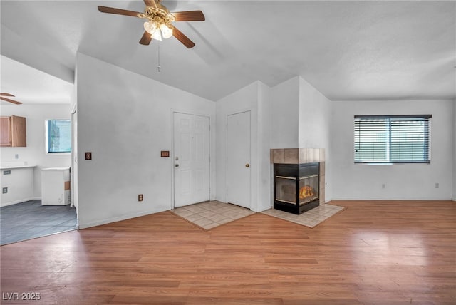 2165 Saint Paul Way, Las Vegas, NV 89104 - unfurnished living room featuring a ceiling fan, light wood-style flooring, plenty of natural light, vaulted ceiling, and a tiled fireplace