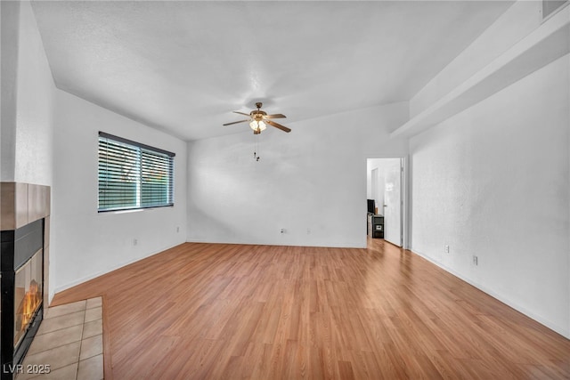 2165 Saint Paul Way, Las Vegas, NV 89104 - unfurnished living room with a tiled fireplace, a ceiling fan, and light wood-style floors