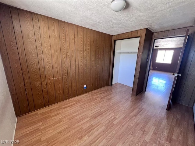 6120 Denver Cir, Las Vegas, NV 89107 - unfurnished bedroom with wooden walls, wood finished floors, a textured ceiling, and a closet