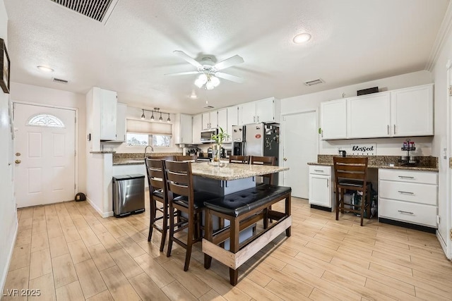6140 Atwood Ave, Las Vegas, NV 89108 - kitchen featuring white cabinetry, light wood-type flooring, ceiling fan, stone countertops, and stainless steel microwave