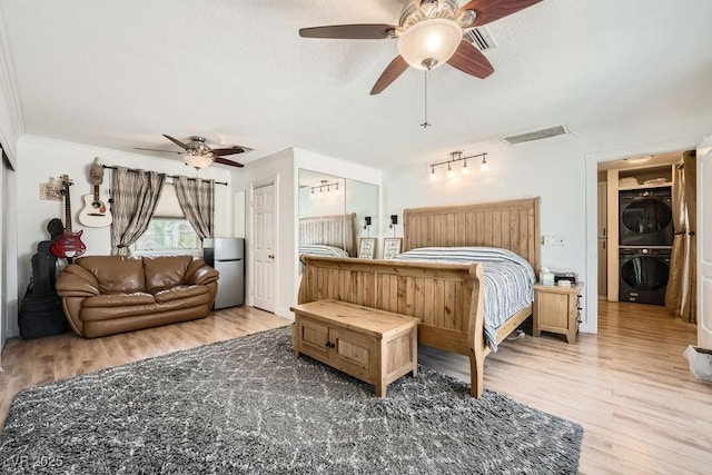 6140 Atwood Ave, Las Vegas, NV 89108 - bedroom featuring stacked washer and clothes dryer, freestanding refrigerator, wood finished floors, crown molding, and two closets