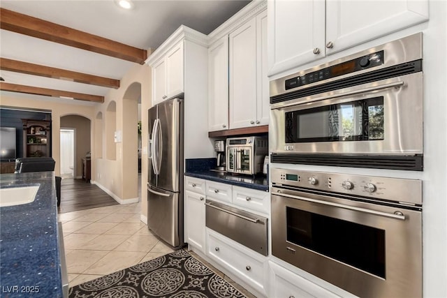 9380 Arrowhead Bluff Ave, Las Vegas, NV 89149 - kitchen with stainless steel appliances, arched walkways, a warming drawer, white cabinets, and beam ceiling