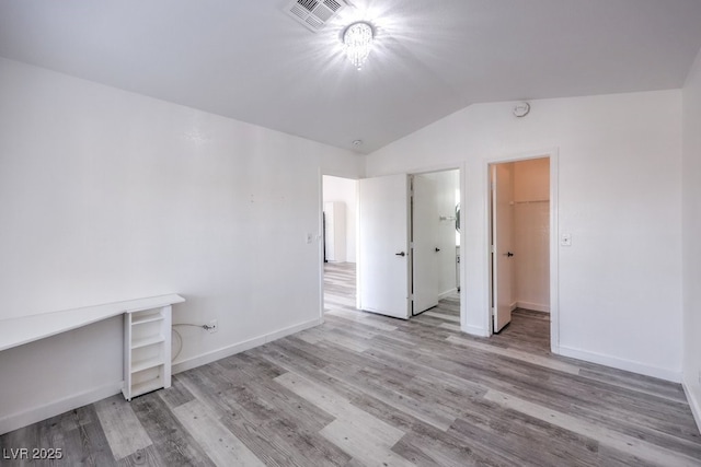5320 Castle Harbor Ave, Las Vegas, NV 89130 - unfurnished bedroom featuring vaulted ceiling, wood finished floors, and a walk in closet