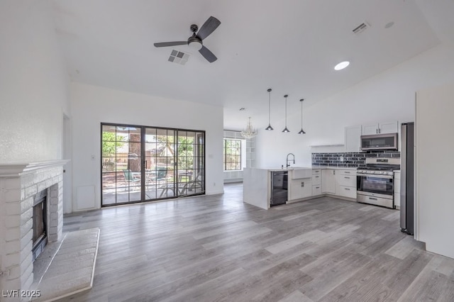 5320 Castle Harbor Ave, Las Vegas, NV 89130 - kitchen featuring appliances with stainless steel finishes, open floor plan, a peninsula, ceiling fan, and a brick fireplace