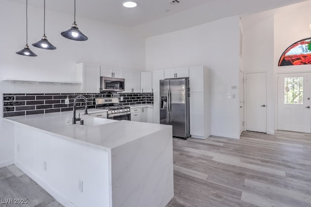 5320 Castle Harbor Ave, Las Vegas, NV 89130 - kitchen featuring stainless steel appliances, high vaulted ceiling, a peninsula, light countertops, and white cabinetry