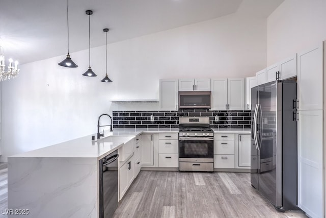 5320 Castle Harbor Ave, Las Vegas, NV 89130 - kitchen featuring appliances with stainless steel finishes, decorative backsplash, a peninsula, light wood-type flooring, and pendant lighting