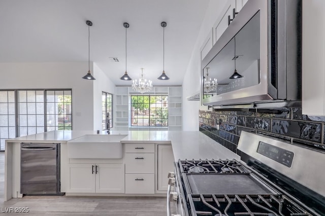 5320 Castle Harbor Ave, Las Vegas, NV 89130 - kitchen with appliances with stainless steel finishes, a chandelier, backsplash, white cabinetry, and a peninsula