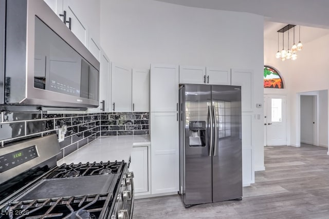 5320 Castle Harbor Ave, Las Vegas, NV 89130 - kitchen featuring appliances with stainless steel finishes, a high ceiling, decorative backsplash, white cabinets, and light wood finished floors