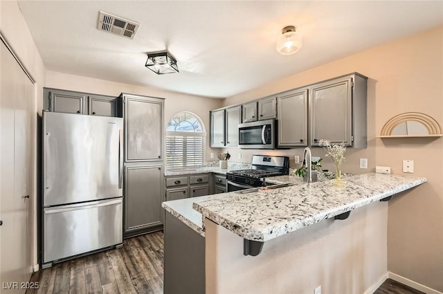 3125 N Buffalo Dr Unit 1090, Las Vegas, NV 89128 - kitchen featuring stainless steel appliances, gray cabinetry, a peninsula, dark wood finished floors, and a kitchen breakfast bar