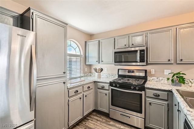 3125 N Buffalo Dr Unit 1090, Las Vegas, NV 89128 - kitchen featuring stainless steel appliances, gray cabinets, wood finished floors, and light stone countertops