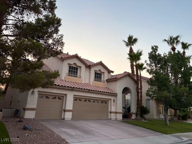 302 Doe Run, Henderson, NV 89012 - mediterranean / spanish-style home featuring a tile roof, stucco siding, driveway, and an attached garage