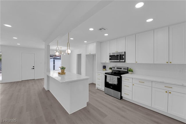 1317 Pyramid Dr, Las Vegas, NV 89108 - kitchen with stainless steel appliances, white cabinetry, light wood finished floors, backsplash, and recessed lighting