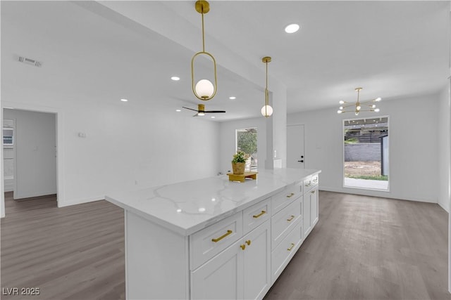 1317 Pyramid Dr, Las Vegas, NV 89108 - kitchen featuring wood finished floors, white cabinets, a center island, pendant lighting, and recessed lighting