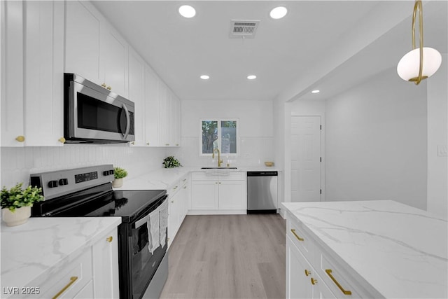1317 Pyramid Dr, Las Vegas, NV 89108 - kitchen featuring appliances with stainless steel finishes, recessed lighting, white cabinetry, light wood-type flooring, and light stone countertops