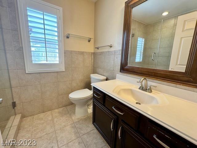 3197 Dusty Moon Ave, Henderson, NV 89052 - full bathroom featuring tile walls, vanity, tile patterned flooring, a shower stall, and a wainscoted wall