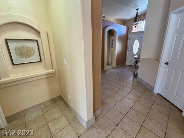 3197 Dusty Moon Ave, Henderson, NV 89052 - hall with arched walkways, light tile patterned floors, and a chandelier