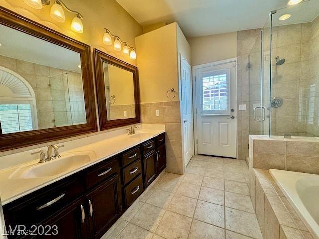 3197 Dusty Moon Ave, Henderson, NV 89052 - bathroom featuring double vanity, tile walls, a garden tub, a shower stall, and tile patterned flooring