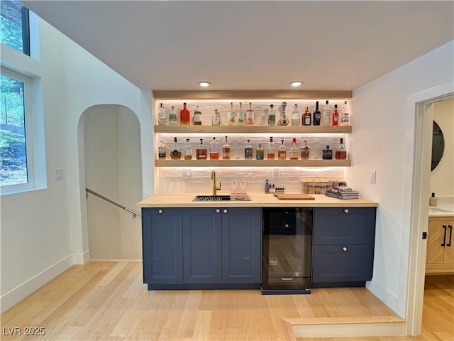 4651 Aspen Ave, Mount Charleston, NV 89124 - indoor wet bar with beverage cooler, light wood-style flooring, tasteful backsplash, arched walkways, and recessed lighting