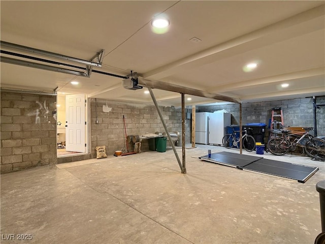 4651 Aspen Ave, Mount Charleston, NV 89124 - garage featuring concrete block wall, freestanding refrigerator, a garage door opener, and recessed lighting