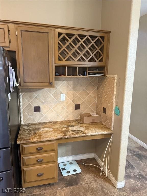5315 Debut Ct, North Las Vegas, NV 89031 - kitchen with freestanding refrigerator, tasteful backsplash, built in study area, and light stone countertops