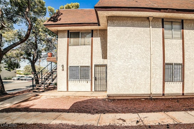 4348 Tara Ave Unit 2, Las Vegas, NV 89102 - view of property exterior featuring stucco siding, stairs, and roof with shingles