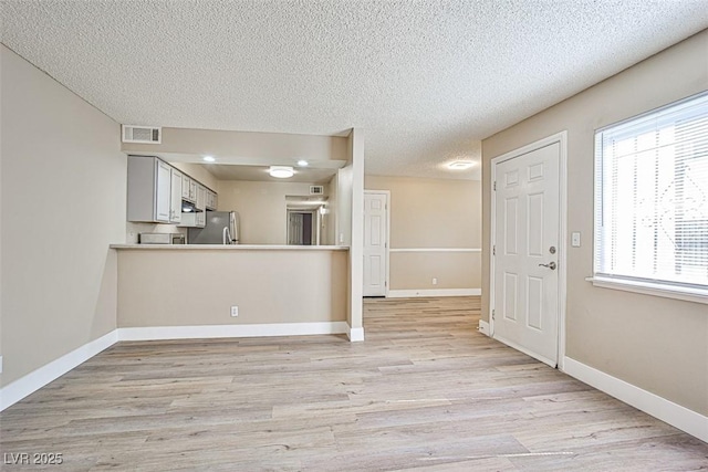 4348 Tara Ave Unit 2, Las Vegas, NV 89102 - kitchen featuring freestanding refrigerator, light wood-style floors, a textured ceiling, and light countertops