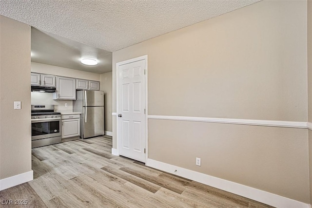 4348 Tara Ave Unit 2, Las Vegas, NV 89102 - kitchen featuring stainless steel appliances, gray cabinetry, under cabinet range hood, light wood-style floors, and a textured ceiling