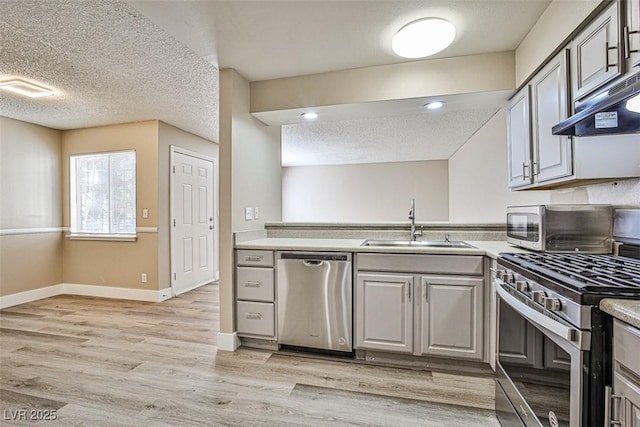 4348 Tara Ave Unit 2, Las Vegas, NV 89102 - kitchen with stainless steel appliances, a textured ceiling, light countertops, light wood-style flooring, and under cabinet range hood