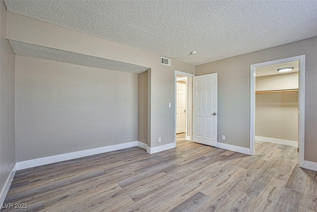4348 Tara Ave Unit 2, Las Vegas, NV 89102 - unfurnished bedroom featuring wood finished floors, a textured ceiling, and a spacious closet