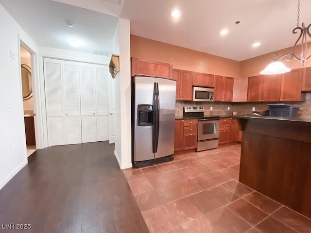 2405 Serene Ave Unit 241, Las Vegas, NV 89123 - kitchen featuring appliances with stainless steel finishes, dark countertops, tasteful backsplash, brown cabinets, and decorative light fixtures