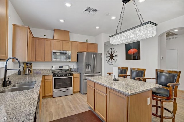 6324 Conlon St, North Las Vegas, NV 89081 - kitchen featuring appliances with stainless steel finishes, arched walkways, light wood-style flooring, a center island, and a breakfast bar area