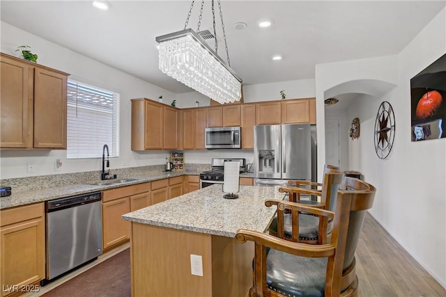 6324 Conlon St, North Las Vegas, NV 89081 - kitchen with stainless steel appliances, a kitchen island, a breakfast bar area, arched walkways, and light stone counters