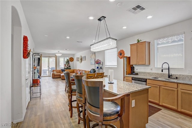 6324 Conlon St, North Las Vegas, NV 89081 - kitchen with a center island, light wood-type flooring, open floor plan, a kitchen bar, and light stone counters