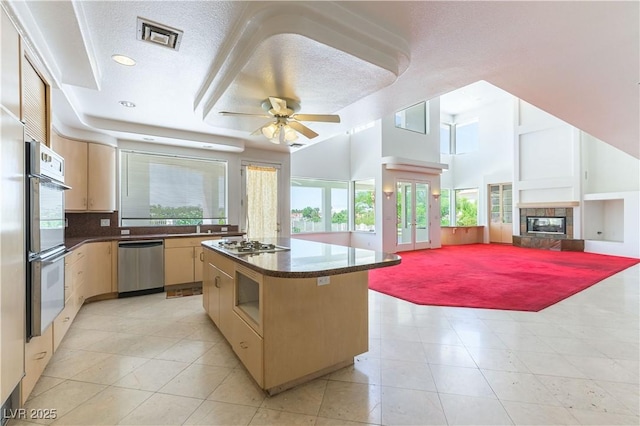2019 Doral Ct, Henderson, NV 89074 - kitchen with appliances with stainless steel finishes, a ceiling fan, dark countertops, a kitchen island, and light tile patterned floors