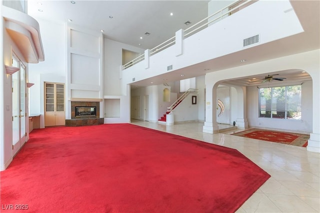 2019 Doral Ct, Henderson, NV 89074 - unfurnished living room featuring arched walkways, a high ceiling, a tile fireplace, tile patterned floors, and a ceiling fan